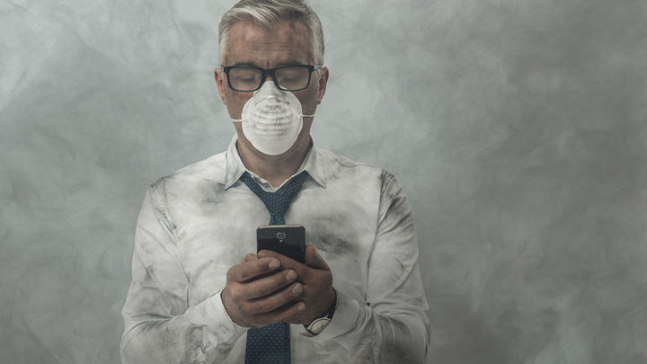 man wearing N95 dust mask and holding cellphone in smokey area