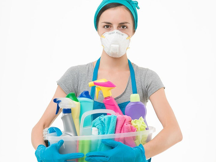 woman wearing dust mask and holding cleaning equipment